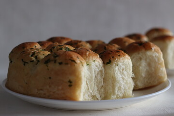 Dinner rolls. Home baked golden brown color dinner rolls fresh from the oven, glazed with butter. Shot on white background along with coriander leaves