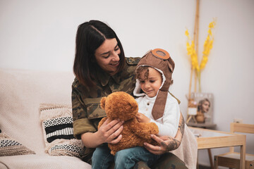 A female soldier returns home from war. The mother brings a gift to her baby and they play together in the living room of their house.