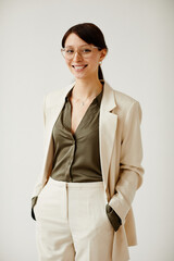 Minimal portrait of successful young woman smiling at camera while standing against neutral...