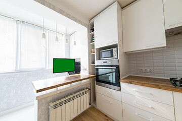 interior of the kitchen and work area with a computer and an armchair on the balcony, loggia. Table top made of solid wood.