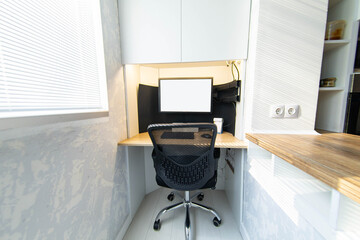 interior of the kitchen and work area with a computer and an armchair on the balcony, loggia. Table top made of solid wood.