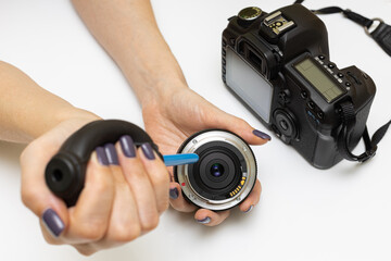 a woman blows dust off a photo lens with a pear