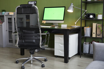Background image of home office workplace with chroma key computer screen on desk against green...