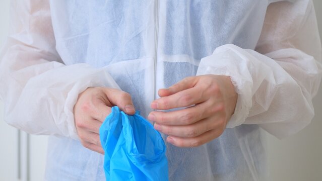 After A Hard Shift In The Infectious Diseases Department, The Doctor Takes Off His Blue Disposable Gloves. The Work Of A Nurse In A Covid Hospital During The Outbreak Of Coronovirus Infection