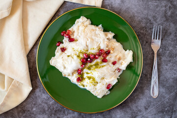 Gullac dessert on dark background. Traditional Ramadan dessert. Güllaç dessert decorated with pistachio and pomegranate. Turkish cuisine delicacies. Top view