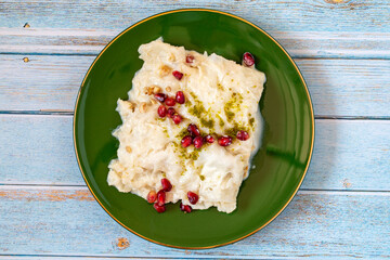 Gullac dessert on wooden background. Traditional Ramadan dessert. Güllaç dessert decorated with pistachio and pomegranate. Turkish cuisine delicacies. Top view