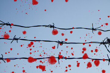 barbed wire against the blue sky. the blood of innocent people. Russia the aggressor attacked.