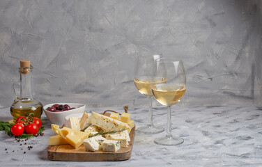 Cheese, olives, cherry and olive oil and glasses with wine, on light background, copy space for wine bottle