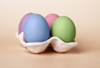 Multicolored dyed Easter eggs in carton box on beige background. Celebration tradition concept. High quality photo
