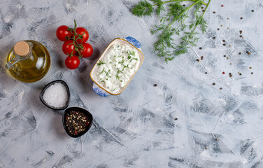 Tzatziki - yoghurt sauce with cucumber and dill on a grey background, traditional Greek cuisine. Flat lay, with copy space. Space for your product.