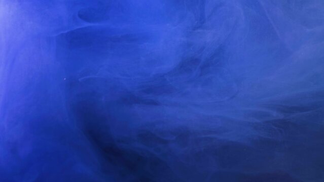 Blue, yellow, gold ink spreading in water. Colored acrylic cloud abstract smoke background. Glitter fluid motion. 