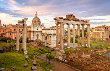 Fototapeta na wymiar View of the temple of Saturn in Roman forum, Italy. Ruins of Septimius Severus Arch and Saturn Temple. Rainbow over the Roman forum. Rome architecture and landmark.