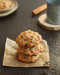 Oatmeal cookies with banana, cinnamon and chocolate drops on the paper print parchment nearby tin...