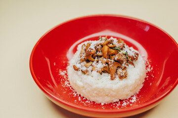 Risotto with mushrooms in a red plate over white background, top view