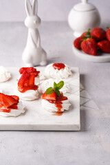 Mini-pavlova with fresh strawberries and red jam - delicious meringue cakes on marble board on...
