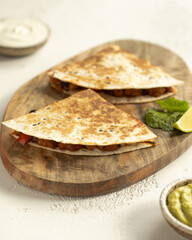 Quesadilla with chicken, guacamole, lime on serving desk