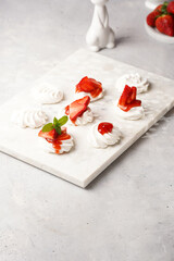 Mini-pavlova with fresh strawberries and red jam - delicious meringue cakes on marble board on...
