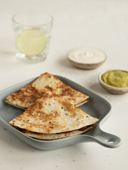 Quesadilla with chicken, guacamole, lime, glass of water with lime