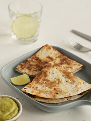 Quesadilla with chicken, guacamole, lime, glass of water with lime
