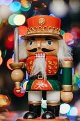 Nutcracker wooden toy on the background of festive Christmas lights. Nutcracker figurine. Bokeh. Christmas. New Year