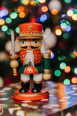 Nutcracker wooden toy on the background of festive Christmas lights. Nutcracker figurine. Bokeh. Christmas. New Year