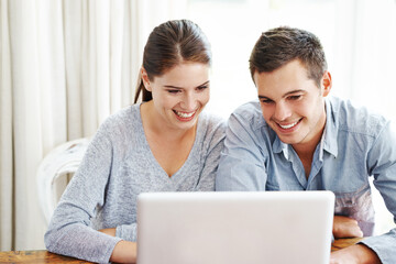 Searching the web together. A young couple using a laptop together at home.