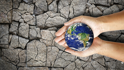 broken world on hands on the dry and cracked ground