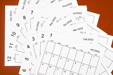Fototapeta na wymiar Many blank monthly 2022 calendar sheets on red background.