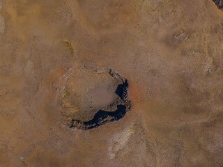 inactive volcanic crater from above. Drone view of landscape in Iceland of Reykjanes Peninsula. brown sand surface and reddish tint around the crater with shadows in sunshine during the day.