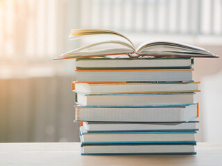 A simple composition of many books, stack or pile of books on wooden table, one of them open with copy space.
