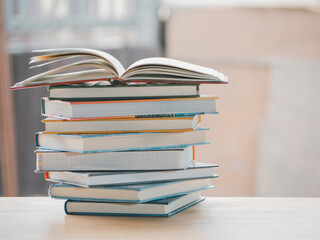 A simple composition of many books, stack or pile of books on wooden table, one of them open with copy space.