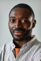 Obraz premium Vertical closeup portrait of adult black man smiling at camera lit by soft light in studio