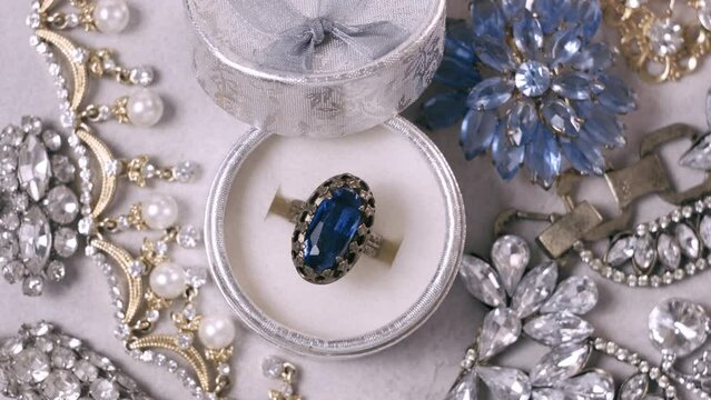 Antique ring with blue gemstone in box and jewel set. Beautiful fashion and vintage jewelry with precious shiny stones, pearls and diamonds for women. Background of Many yellow white gold and silver j