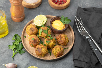 Chickpea falafel with lime and sauce on a plate and grey table