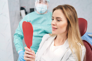 Woman looking in the mirror in dental clinic