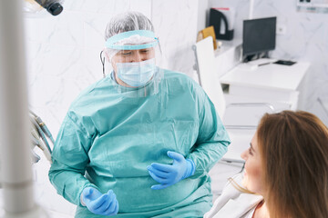 Dentist in medical mask talking with patient in dental clinic