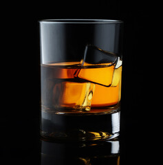 Scotch whiskey in an elegant glass with ice cubes on black background.
