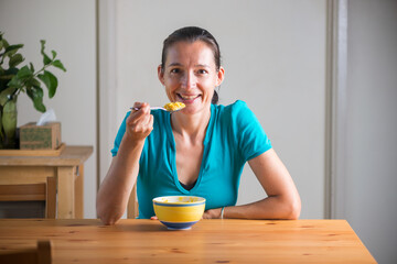Smiling woman eating kitchari for a breakfast.