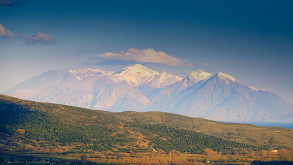 View of the highest snowy mountain of Samothrace island from the center of Gökçeada, Turkey. Greenery and sea view along the valley.
