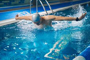 Young man training in pool in evening time