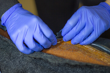 The process of tightening the car interior.Tailor's hands in blue gloves while working with...