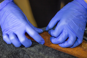 The process of tightening the car interior.Tailor's hands in blue gloves while working with fabric.Tightening of the car interior.The hands of a girl in blue gloves during work are selective focus.