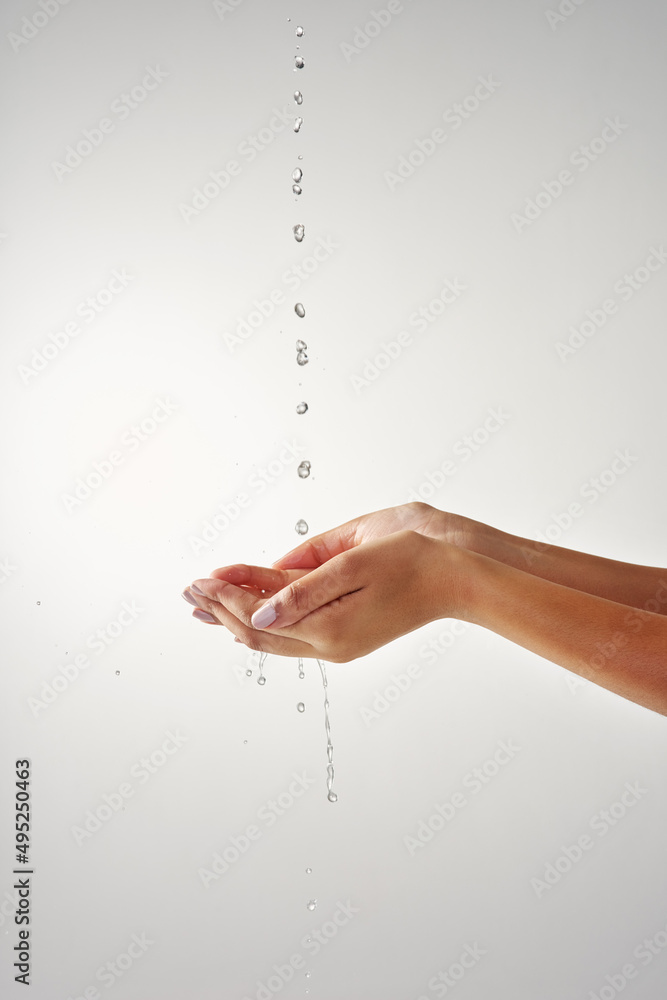 Poster precious and pure. cropped shot of hands held out under a stream of water against a grey background.