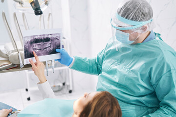 Naklejka na ściany i meble Dentist showing dental scan to woman in stomatology clinic