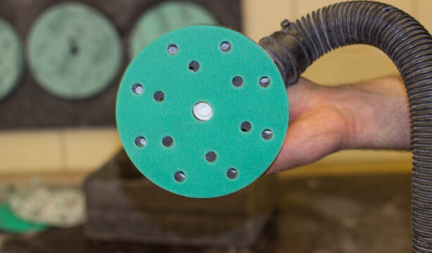 A person changes green sandpaper for a sander.  The master changes the emery wheel on the grinder.  An abrasive disc for an orbital grinder.