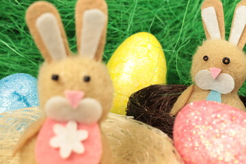 Two easter bunnies in cute nests surrounded by colorful easter eggs. 