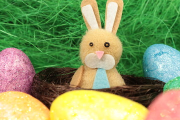 Single easter bunny sitting in a cute nest surrounded by colorful easter eggs