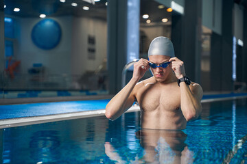 Male standing in pool and getting ready to swim