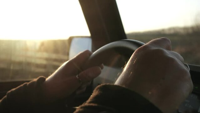 men's hands on the steering wheel close-up  sunset
