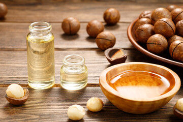 Fototapeta na wymiar Macadamia oil and Macadamia nuts on a wooden background. Natural vitamins.